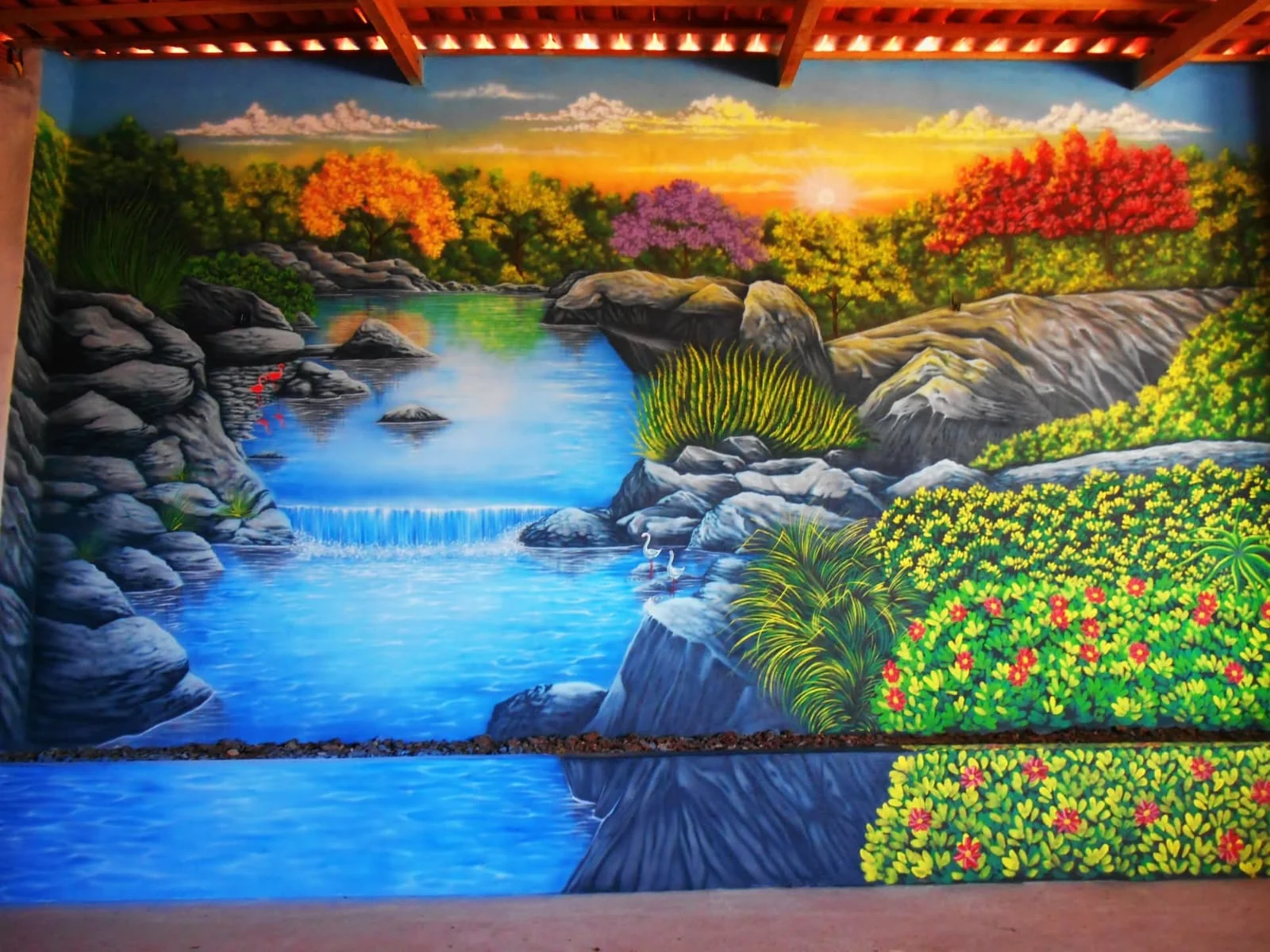 Mural de paisagem com rio, rochas, árvores e flores.